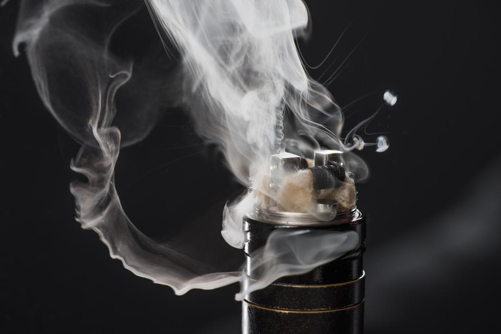 Activating electronic cigarette with clouds of smoke on dark background - Photo, Image