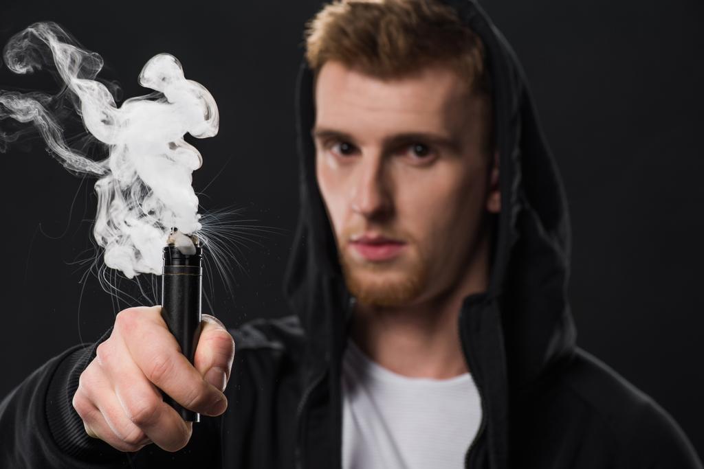 Homem barbudo jovem ativando cigarro eletrônico
 - Foto, Imagem