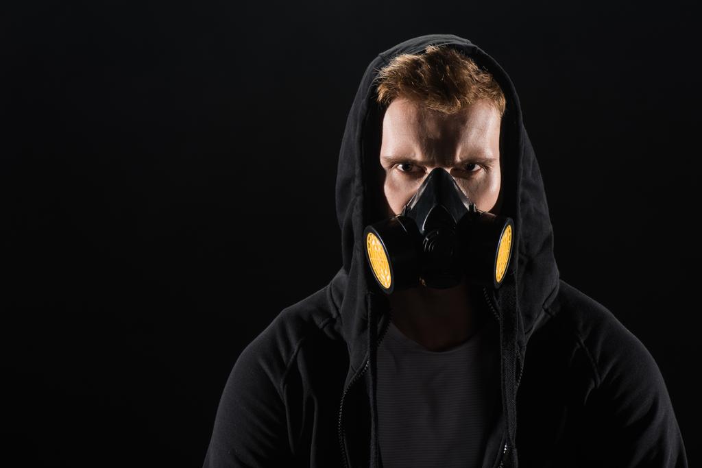 Homem de capuz preto usando máscara protetora de filtro isolado em preto
 - Foto, Imagem
