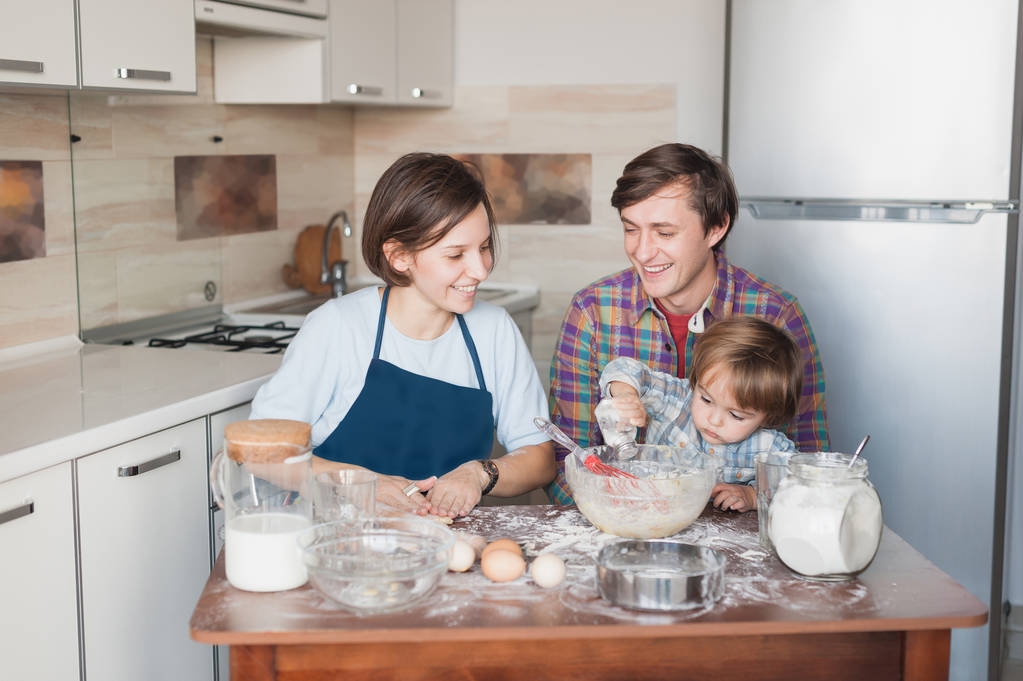 маленька дитина допомагає батькам з приготуванням печива на кухні
 - Фото, зображення