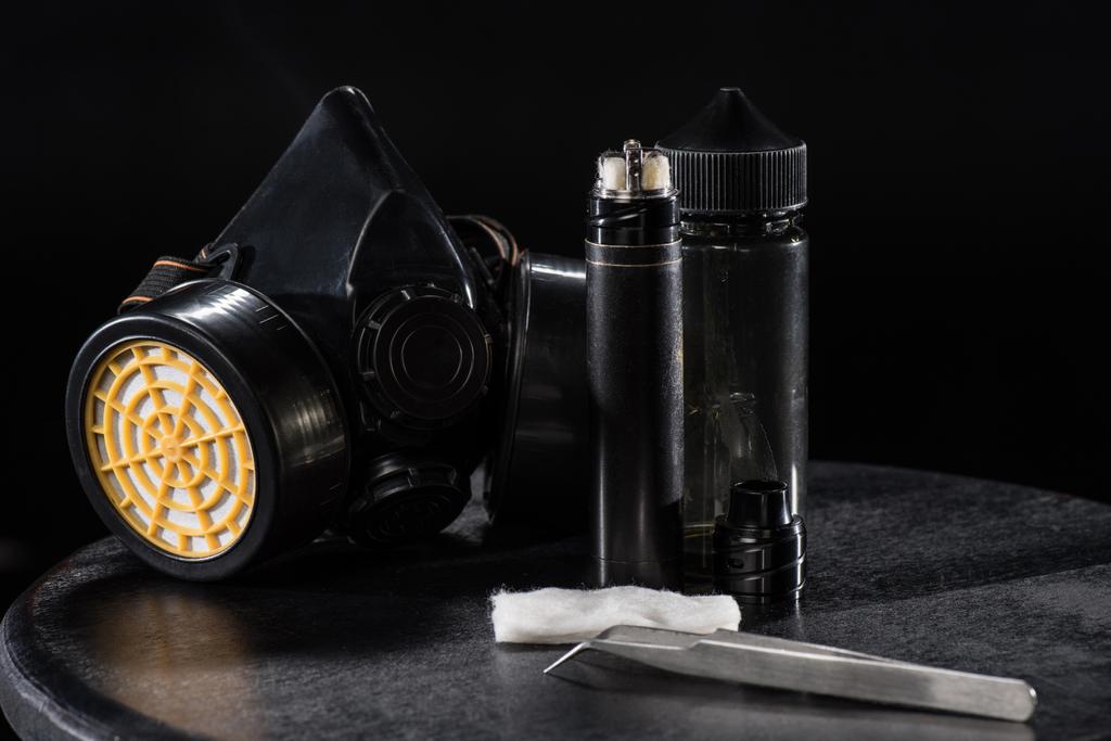Cigarro eletrônico e máscara protetora de filtro isolado em preto
 - Foto, Imagem