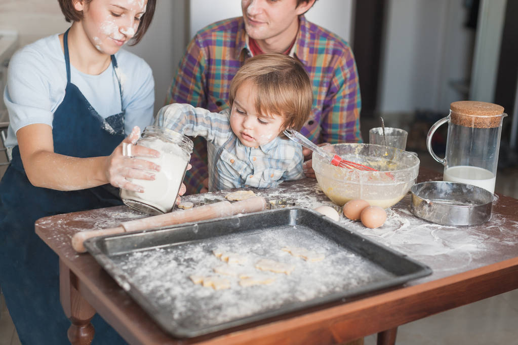 pequena criança ajudando seus pais com cozinhar na cozinha
 - Foto, Imagem
