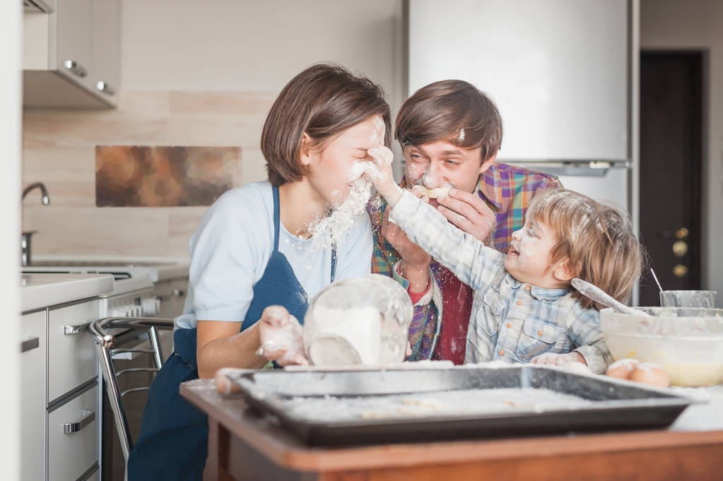 Szczęśliwa rodzina młodych zabawy z mąki w kuchni podczas pieczenia - Zdjęcie, obraz