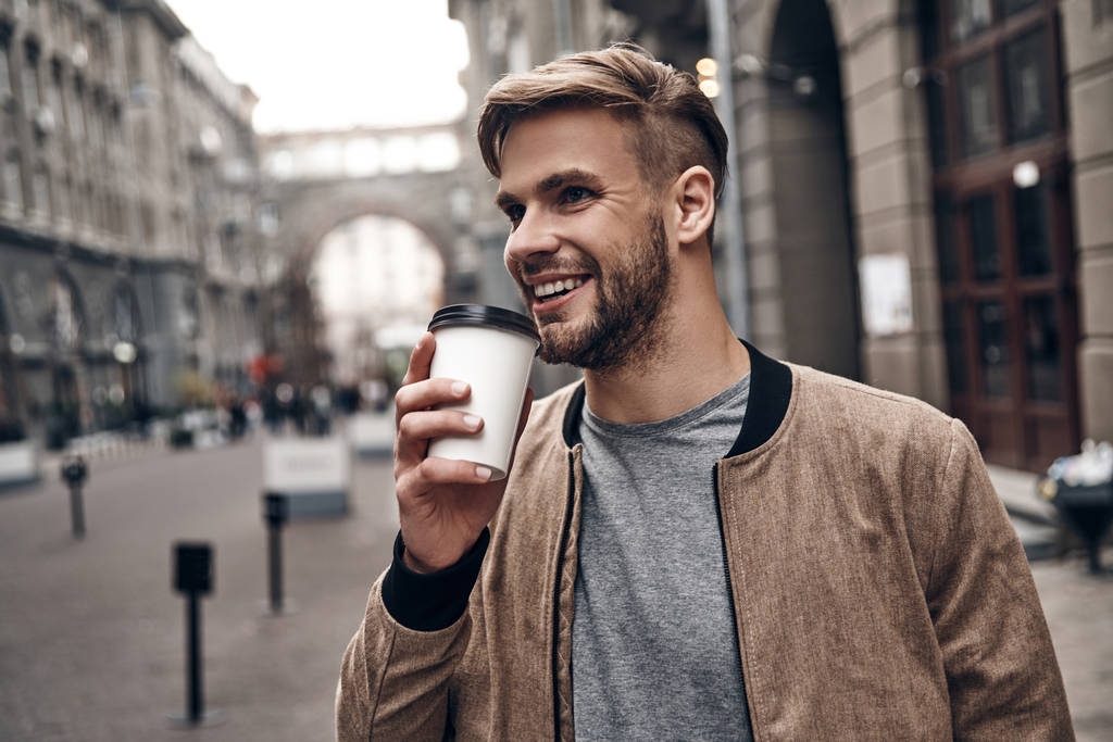 Joven guapo disfrutando de café fresco en la calle de la ciudad
 - Foto, Imagen