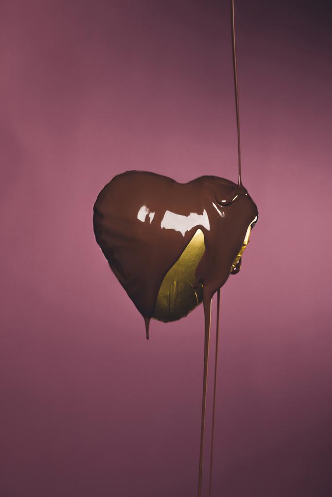 heart shaped candy in golden wrapper with pouring liquid chocolate isolated on pink - Photo, Image