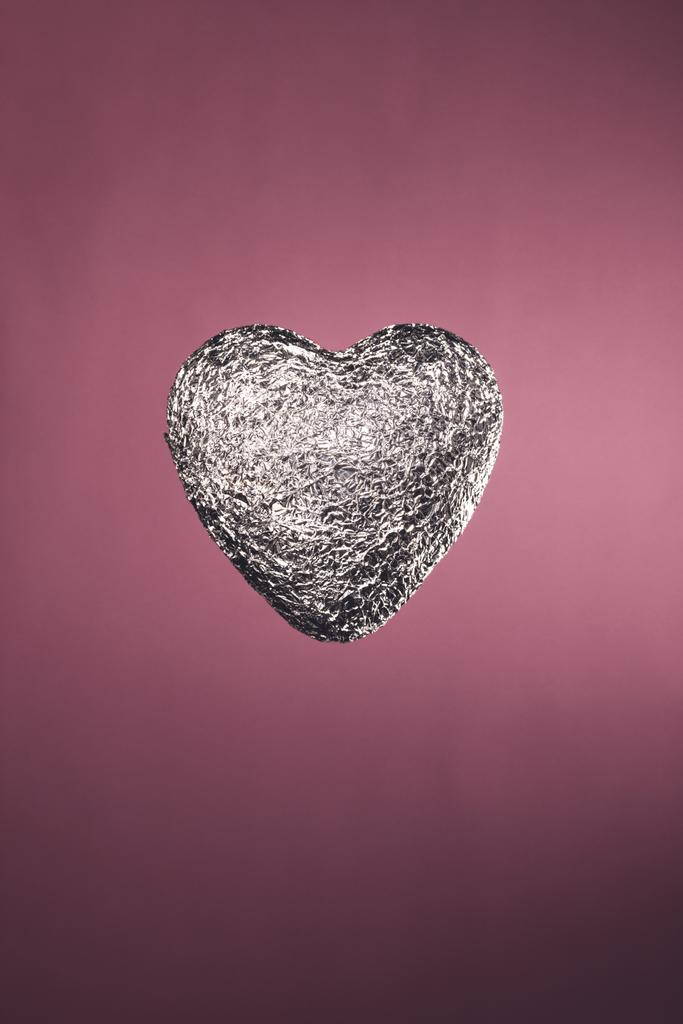 hartvormige snoep in zilveren wrapper geïsoleerd op roze - Foto, afbeelding