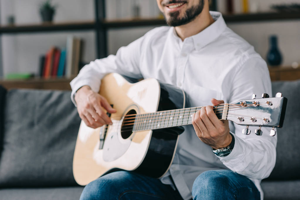 rajattu kuva hymyilevä muusikko pelaa akustista kitaraa
 - Valokuva, kuva