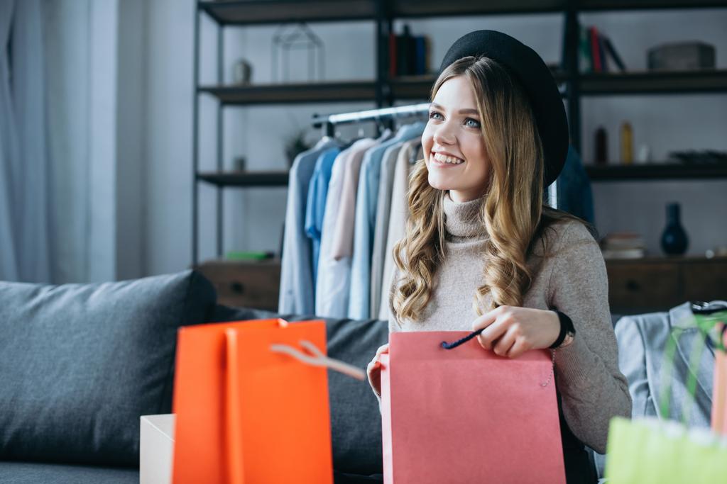 sonriente blogger de moda sentado con bolsas de compras
 - Foto, Imagen