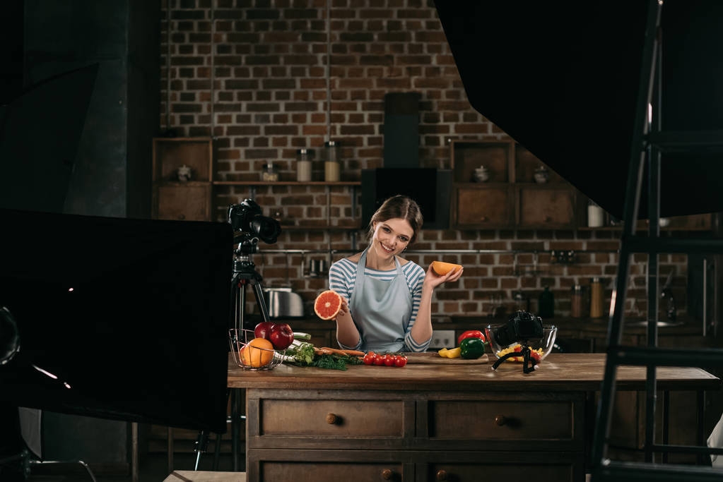 hymyilevä nuori ruoka bloggaaja tilalla puolikkaat greippi käsissä
 - Valokuva, kuva