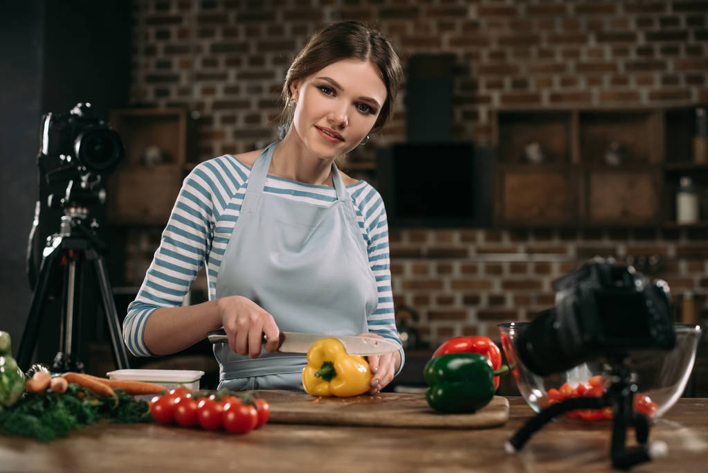 jeune blogueur alimentaire couper les poivrons bulgares et regarder la caméra
 - Photo, image