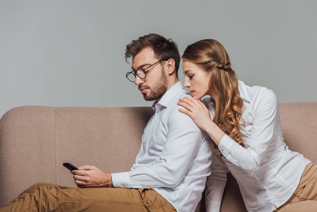 Nuori nainen etsii poikaystävä käyttää älypuhelinta sohvalla eristetty harmaa
 - Valokuva, kuva