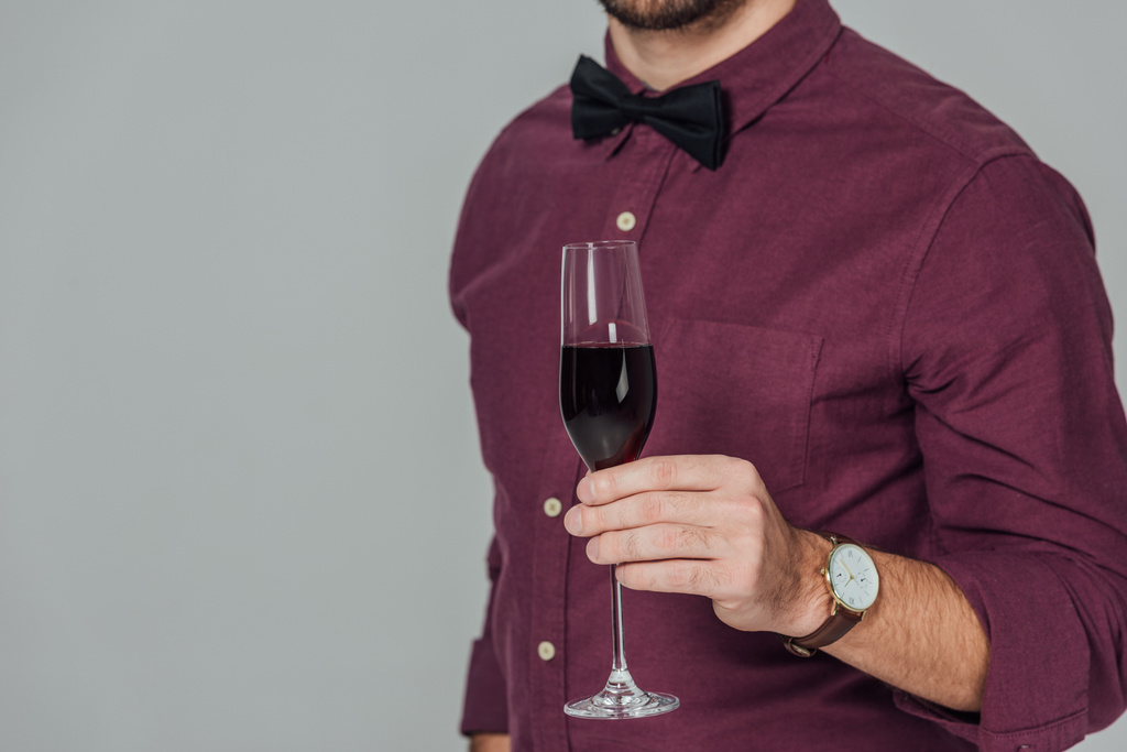 foto recortada de un joven sosteniendo un vaso de vino tinto aislado en gris
 - Foto, imagen