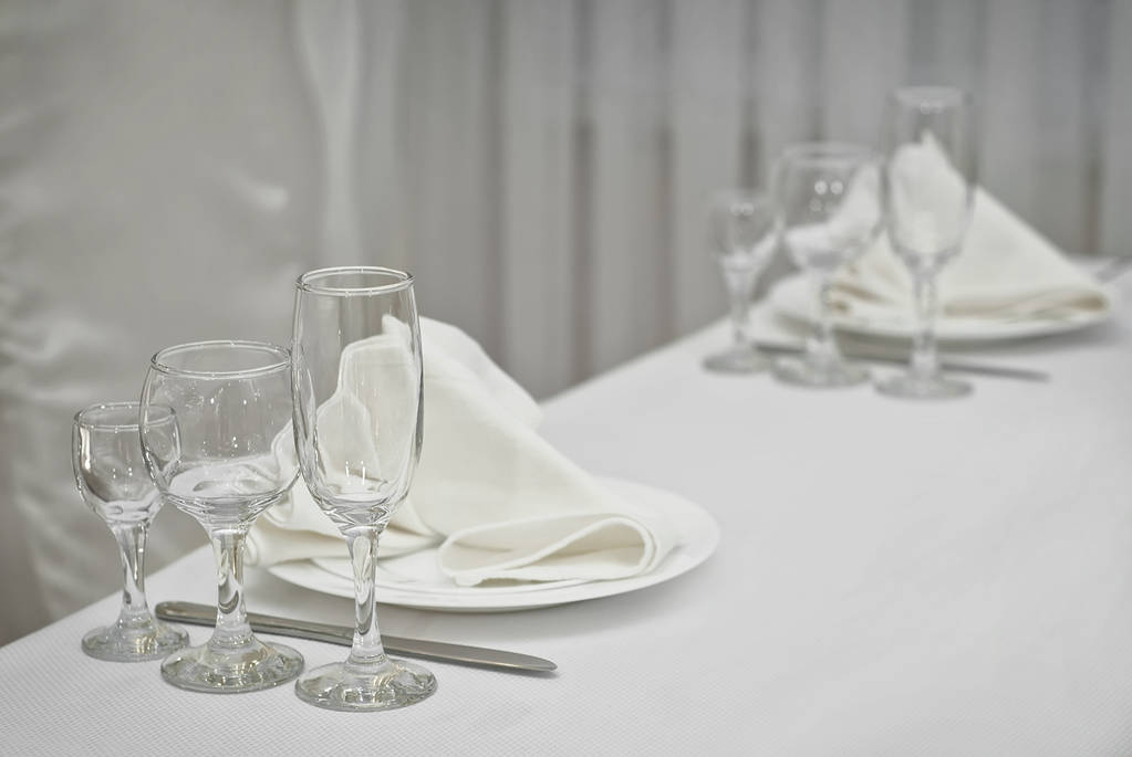 Γυάλινα πιάτα σε ένα τραπέζι σε ένα λευκό τραπεζομάντιλο - Φωτογραφία, εικόνα