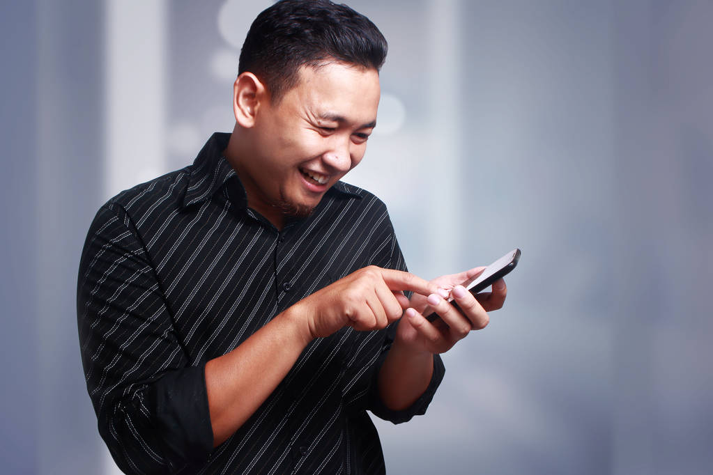 Jonge Man Texting lezing chatten op zijn telefoon, glimlachend gelukkig - Foto, afbeelding