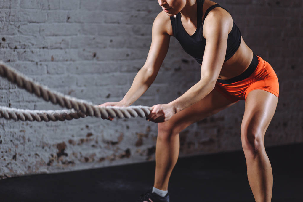Mulher treinando com corda de batalha em cross fit ginásio
 - Foto, Imagem