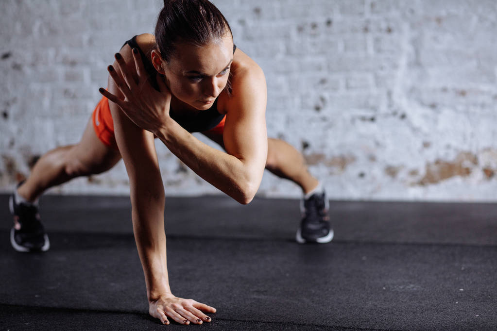 mooie vrouw in sportkleding plank terwijl trainnig bij cross fit gym doen - Foto, afbeelding