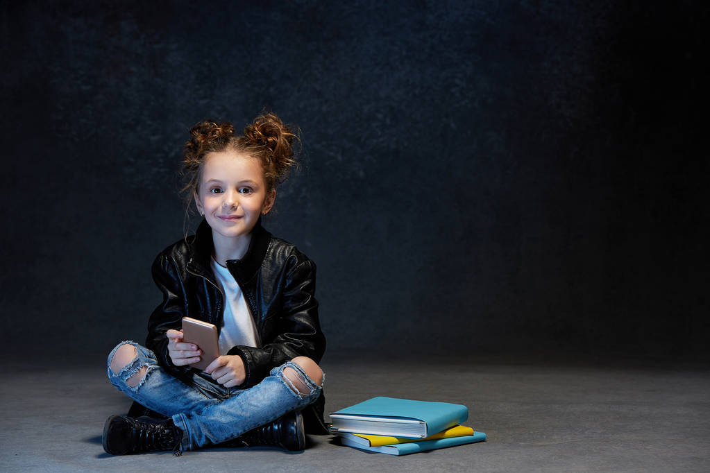 Meisje zittend met smartphone in studio - Foto, afbeelding