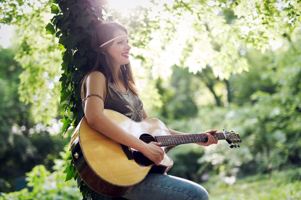 Mujer hermosa tocando la guitarra acústica en la naturaleza
 - Foto, Imagen