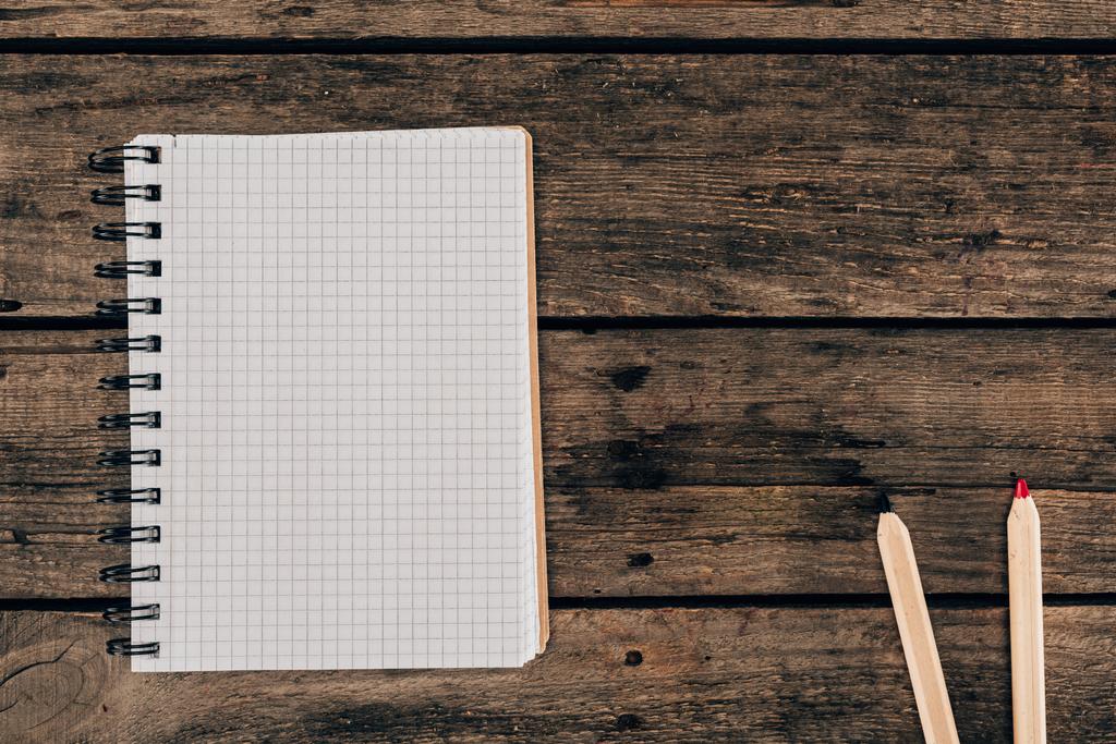 Pohled shora složení barevných tužek s prázdnou notebook na dřevěné pozadí - Fotografie, Obrázek