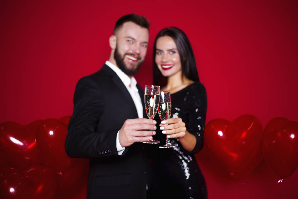Elegáns szép mosolygó pár szerelmesek pohár pezsgő golyó, szív alakú piros alapon. Női-nap március 8-án. Valentin-nap - Fotó, kép