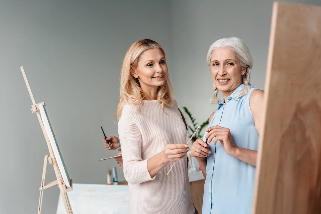 souriantes femmes âgées peignant ensemble en classe d'art
 - Photo, image
