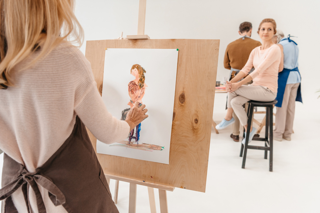 女性モデル アート スタジオの椅子に座って、イーゼルの絵画のクロップ撮影 - 写真・画像