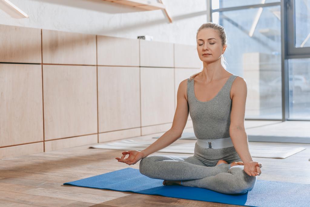 Frau meditiert mit geschlossenen Augen in Lotus-Yoga-Pose mit Mudra des Wissens - Foto, Bild