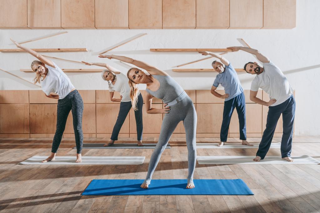 group of senior people stretching with instructor on mats in studio - Photo, Image