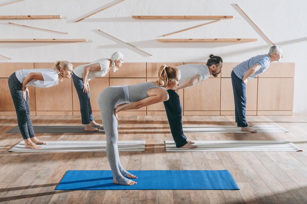 group of senior people practicing yoga with instructor on mats in studio - Photo, Image