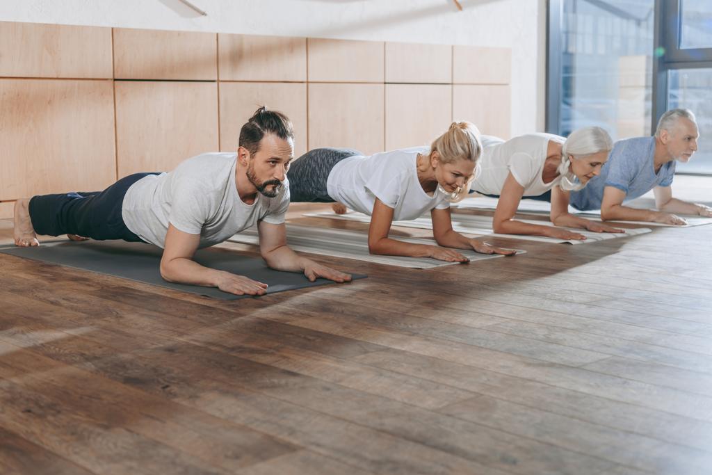 groupe de personnes faisant planche sur tapis de yoga en studio
 - Photo, image