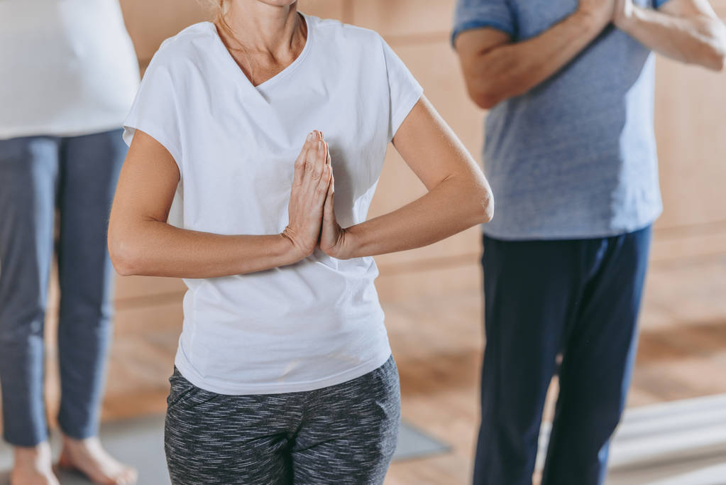 cropped shot of mature people with namaste sign practicing yoga together - Photo, Image
