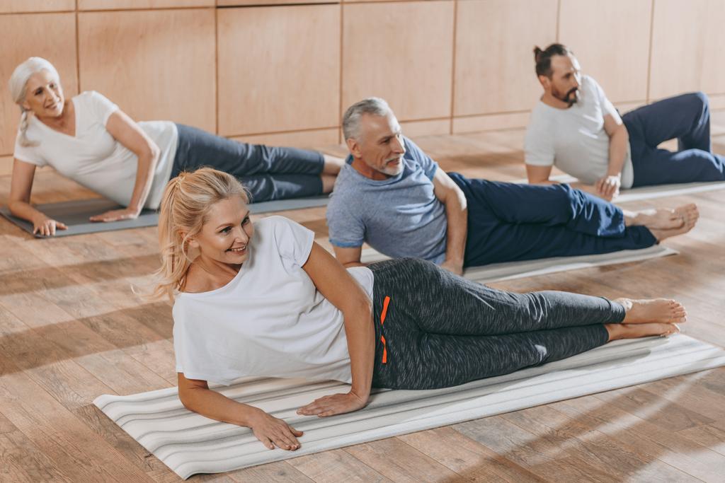 sonriendo personas mayores entrenando en colchonetas de yoga en clase de entrenamiento
 - Foto, imagen