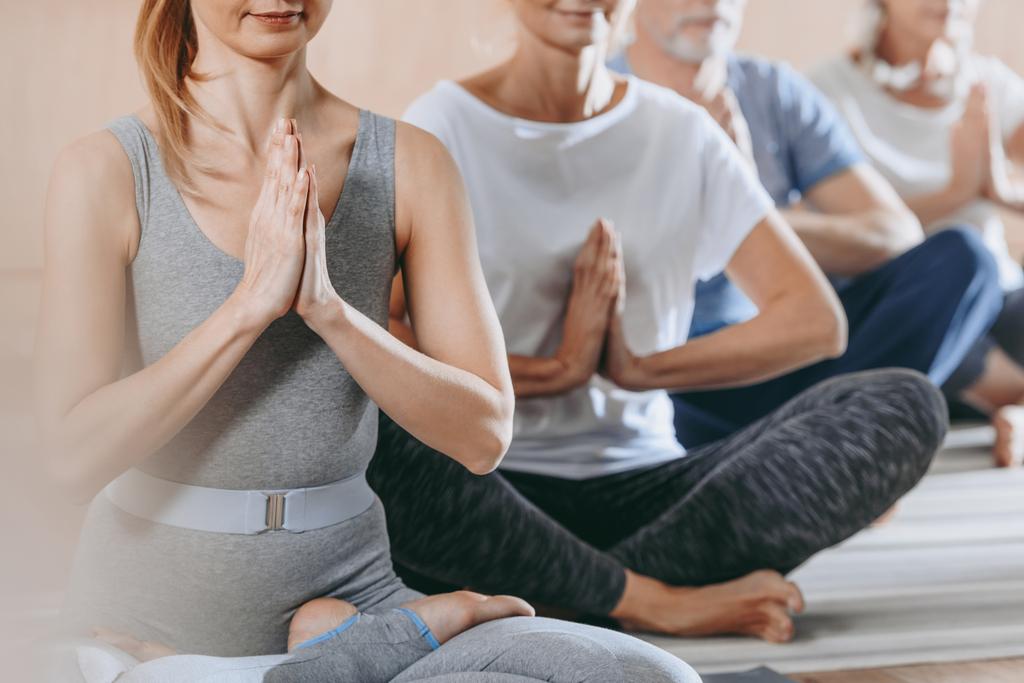 cropped shot of senior people with instructor sitting in lotus position on yoga mats - Photo, Image