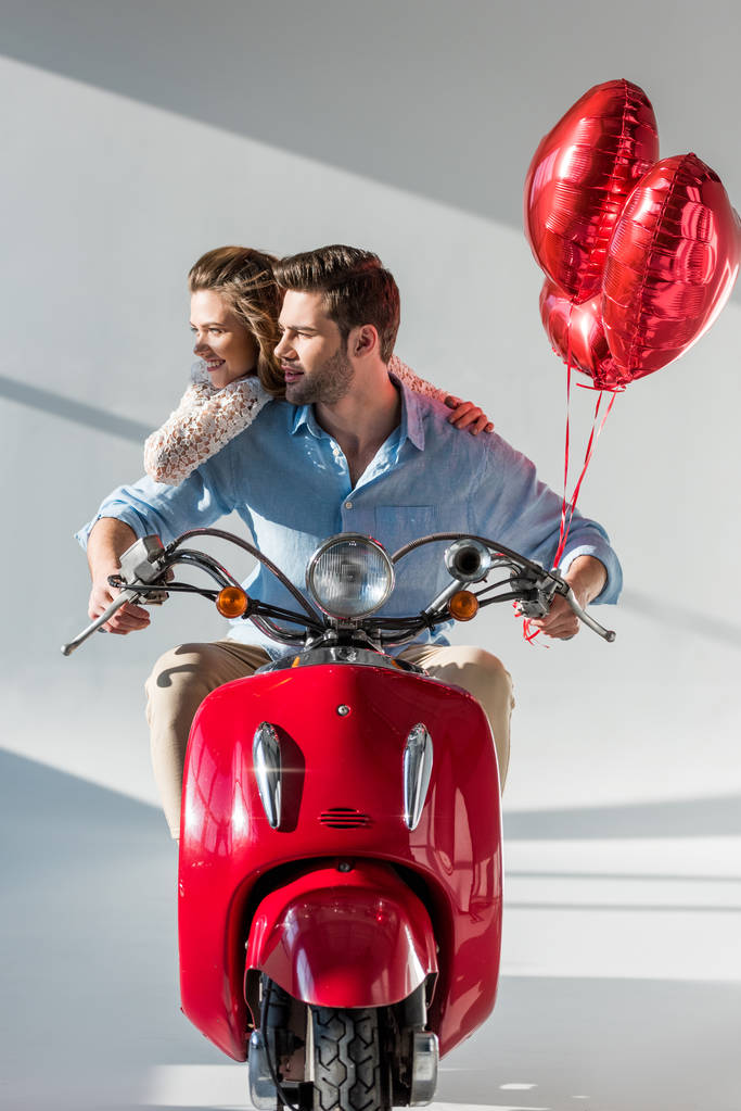 usmíval se mladý pár s červeným srdcem ve tvaru bubliny jezdecké skútr - Fotografie, Obrázek