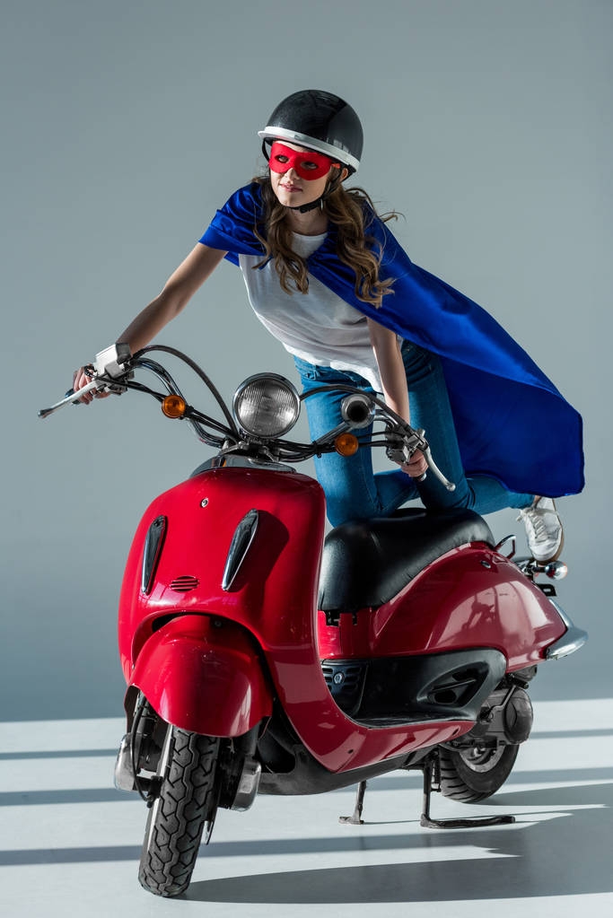 Kobieta w maska superbohatera i cape i kask ochronny jazda czerwony hulajnoga - Zdjęcie, obraz