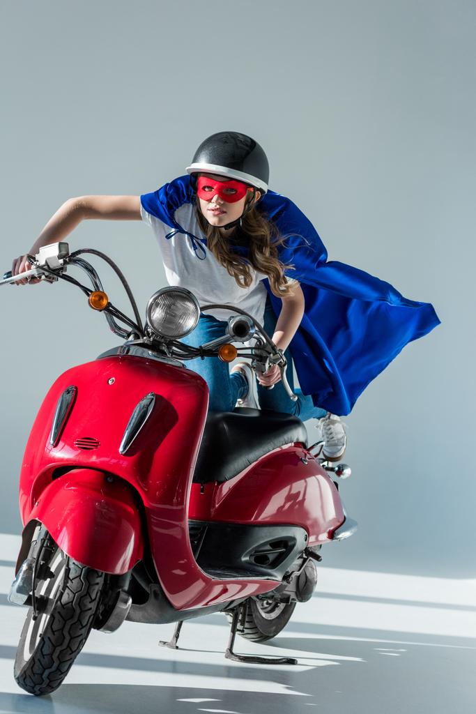 Frau im Superheldenkostüm und Schutzhelm auf rotem Roller - Foto, Bild