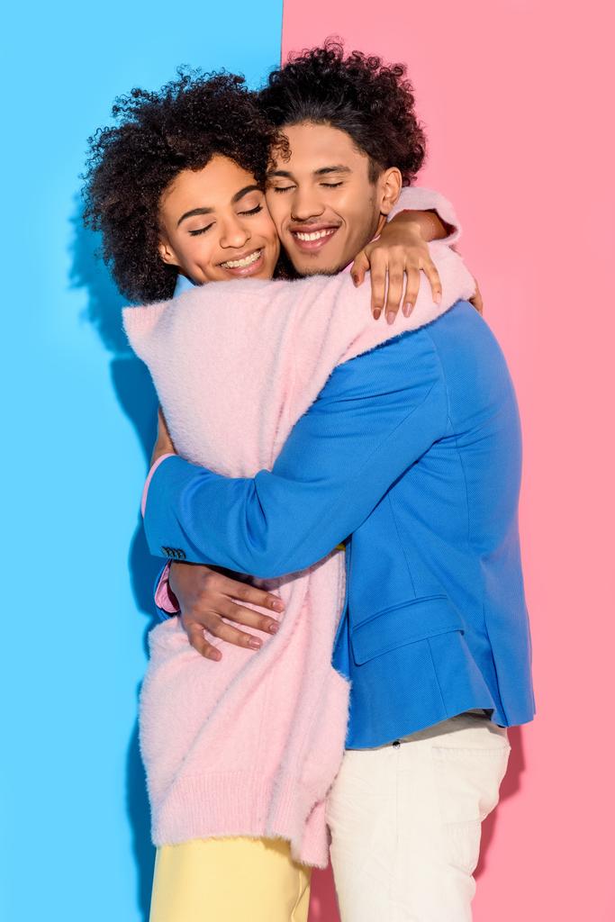 encantadora pareja joven abrazándose unos a otros sobre fondo rosa y azul
   - Foto, imagen