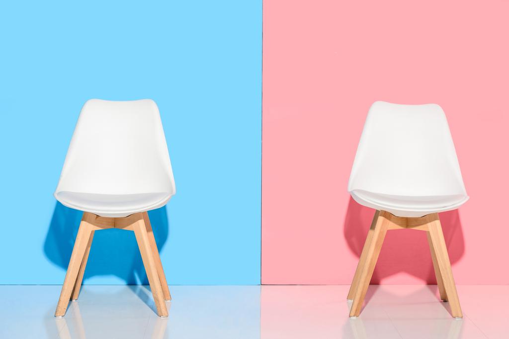 Nahaufnahme weißer Stühle gegen blaue und rosa Wand - Foto, Bild
