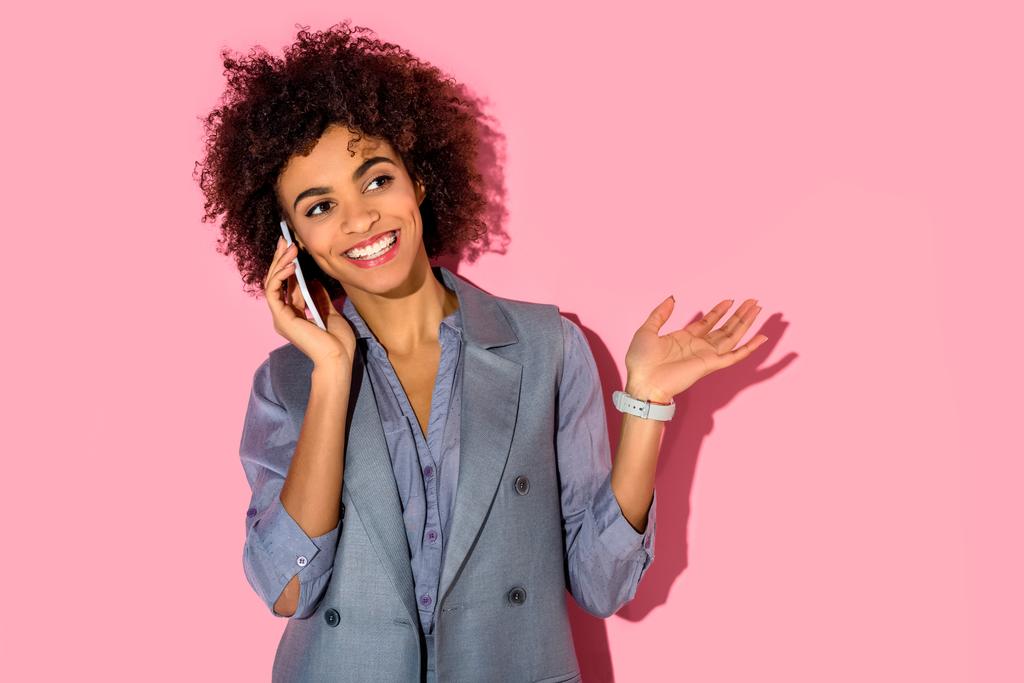 Joven mujer de negocios amerciana africana hablando por teléfono sobre fondo rosa
  - Foto, imagen