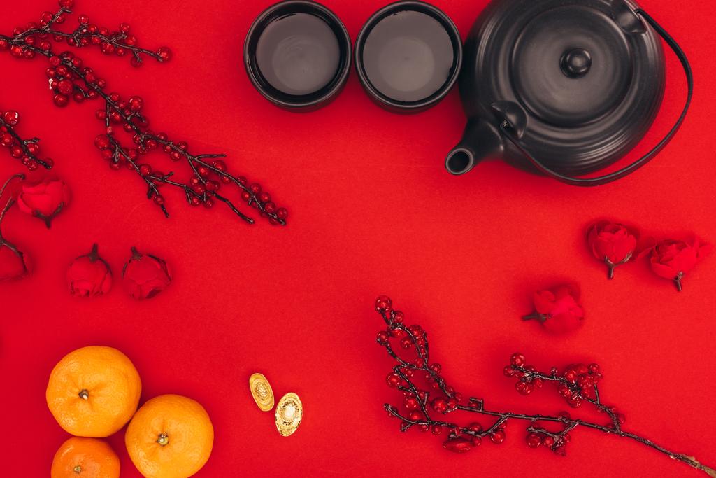 top view of chinese new year composition with tea and branches of berries on red - Photo, Image