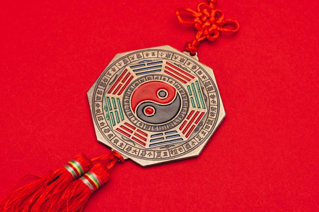 close-up tiro de yin chinês e yang talisman na superfície vermelha
 - Foto, Imagem