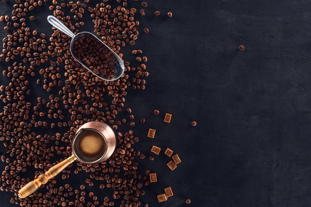 верхний вид организованной кофе пивовар, металлический совок и жареный кофе в зернах на темной поверхности
 - Фото, изображение