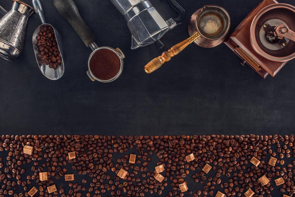 vista superior de grãos de café torrados com açúcar mascavo e várias cafeteiras e moedores em preto
 - Foto, Imagem