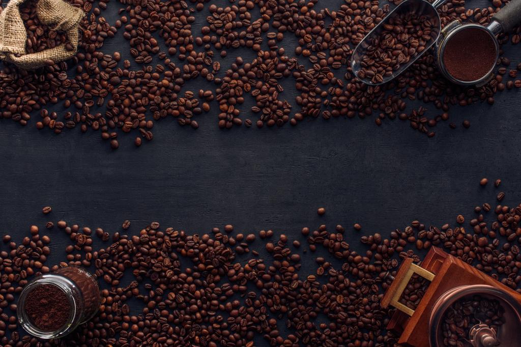 vista superior de granos de café tostados, saco, molinillo de café y cucharada en negro
 - Foto, imagen