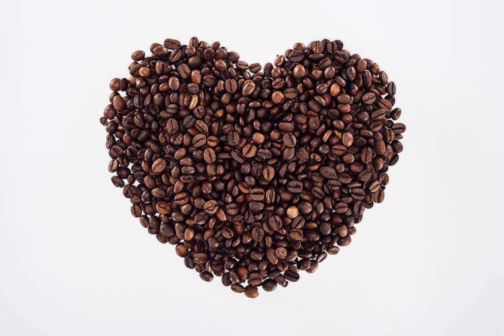 kavrulmuş kahve çekirdekleri üzerine beyaz izole yapılan kalp yakından görmek  - Fotoğraf, Görsel