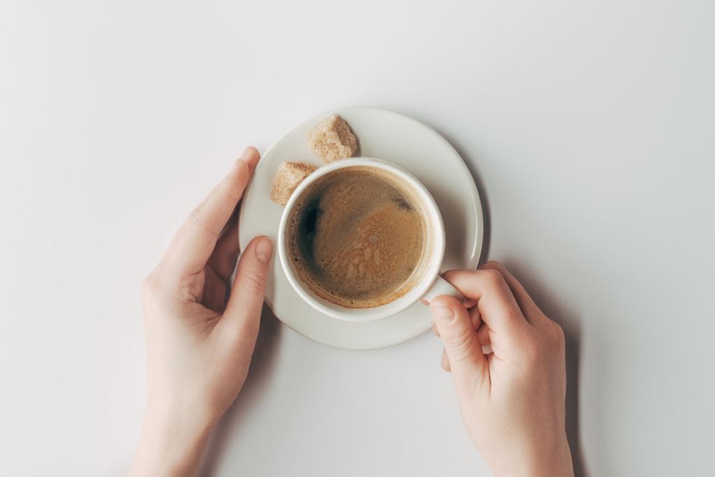 κάτοψη του ανθρώπινα χέρια και φλιτζάνι καφέ με ζάχαρη σε λευκό - Φωτογραφία, εικόνα