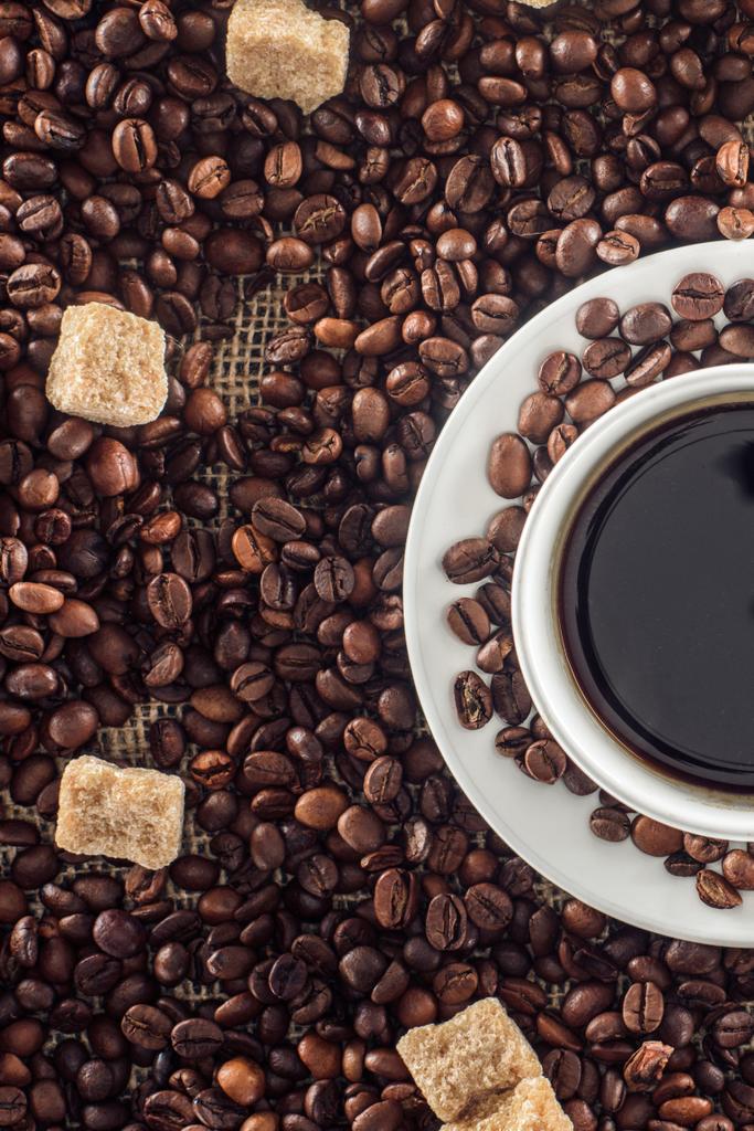 φλιτζάνι καφέ, φρυγμένους κόκκους καφέ και καφέ ζάχαρη σε λινάτσα   - Φωτογραφία, εικόνα