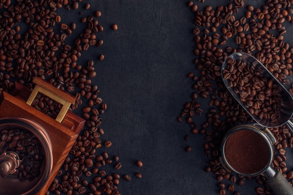 vista superior de granos de café tostados, molinillo de café y cucharada en negro
 - Foto, imagen