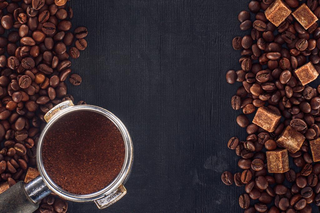pohled shora pražených kávových zrn s hnědým cukrem a kávou pěch na černém pozadí - Fotografie, Obrázek