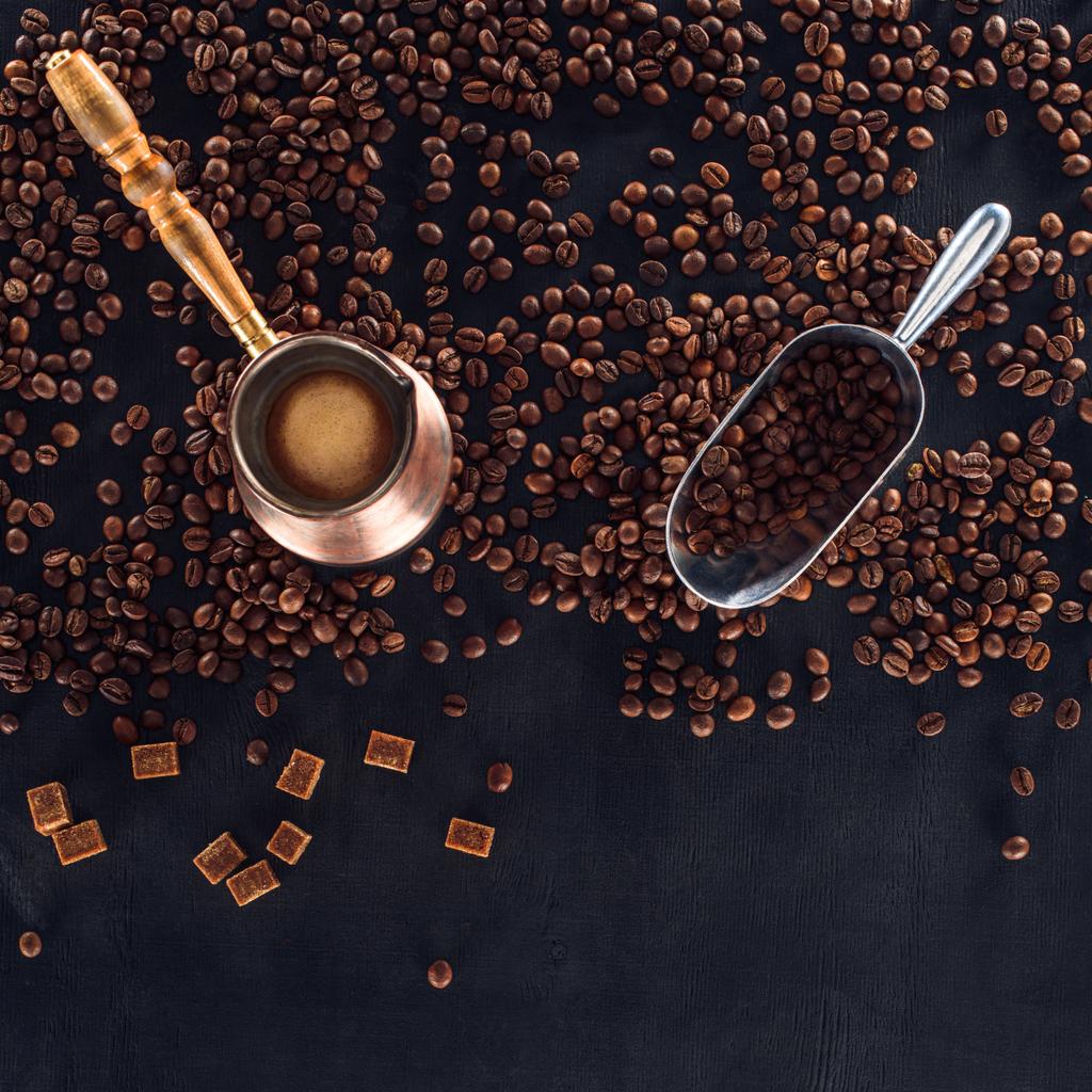 pohled shora pražená kávová zrna, lopatka a hrneček na kávu na černém pozadí - Fotografie, Obrázek